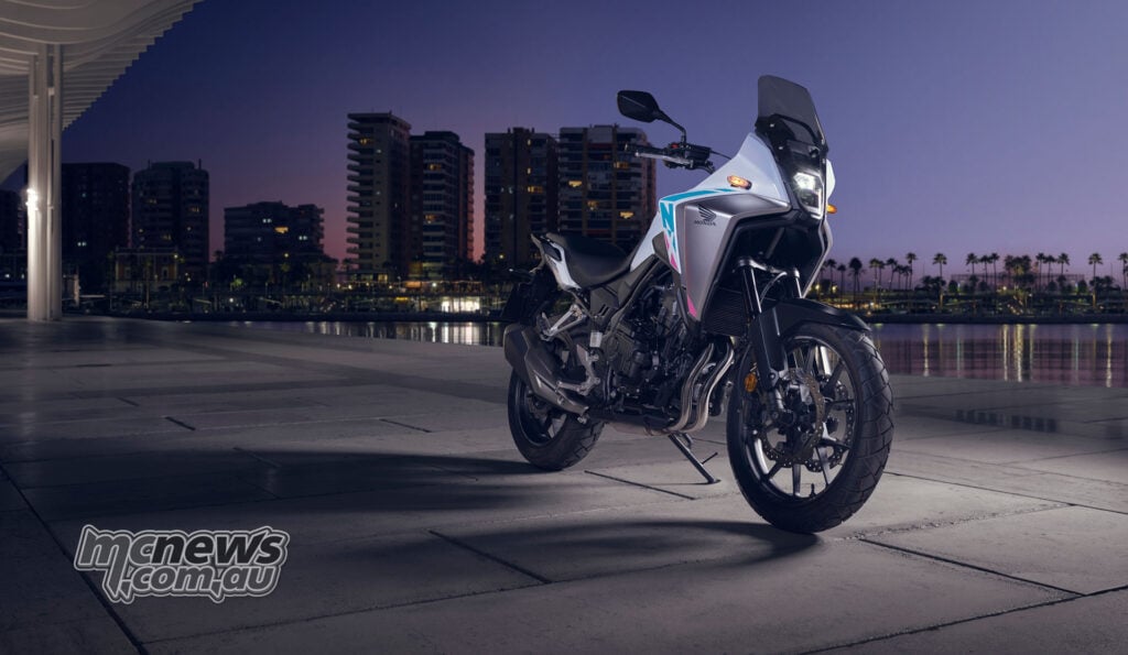 White 2026 Honda NX500 parked beside a waterfront cityscape at dusk