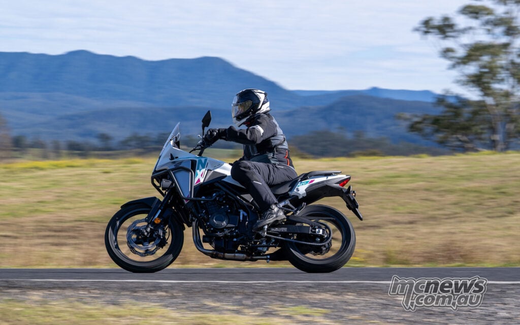 Trevor Hedge riding a white 2026 Honda NX500 with mountains in the background