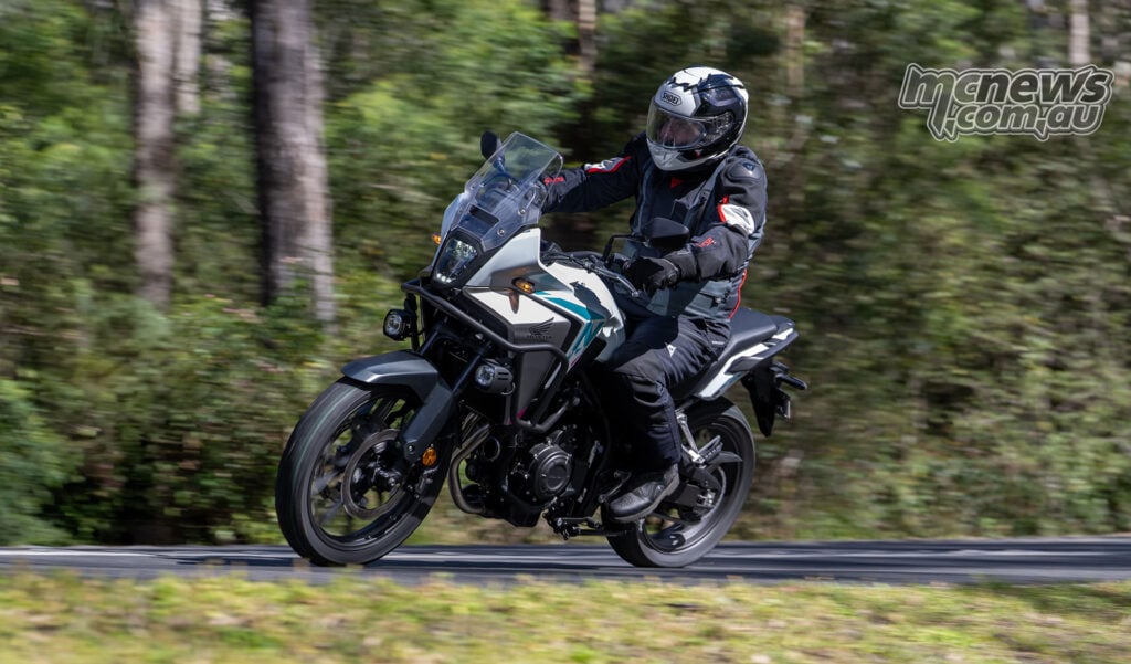 Trevor Hedge riding a white Honda NX500 through a forested section of road