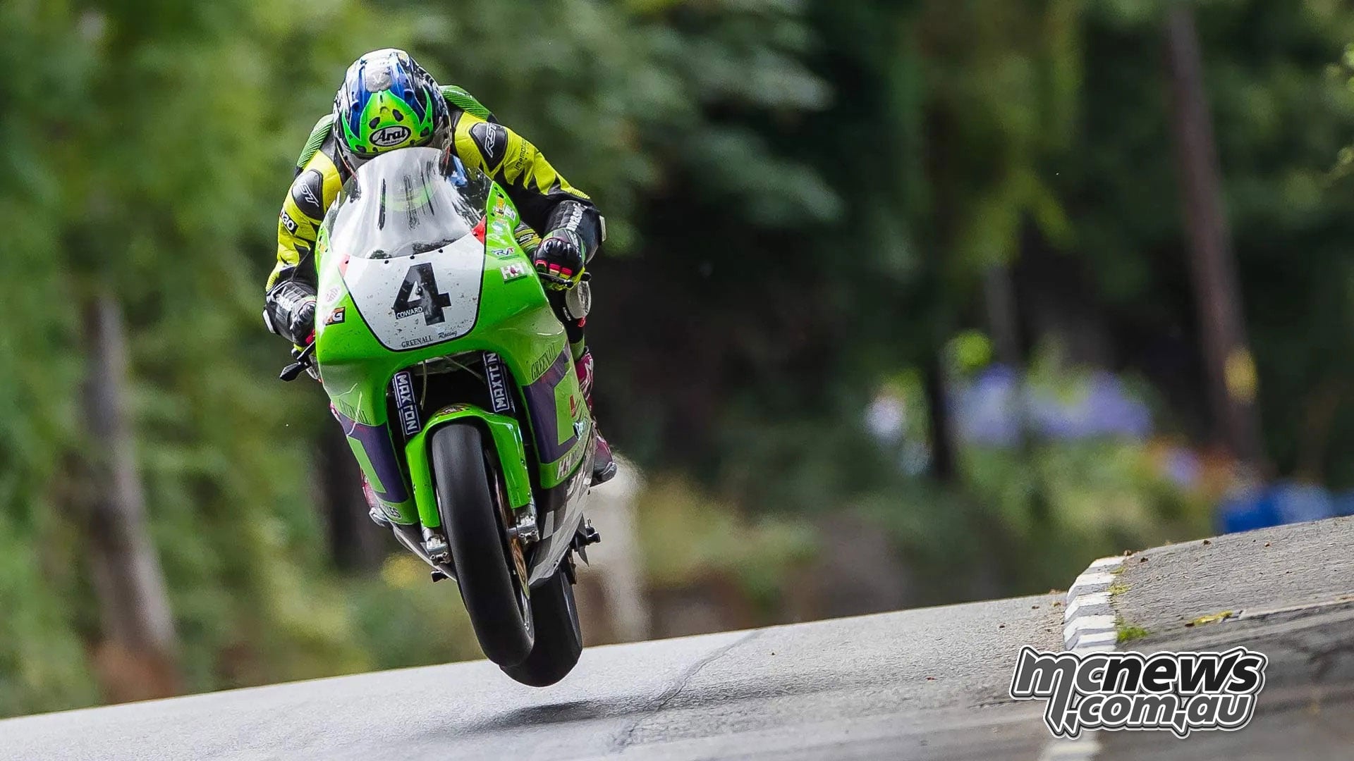 Jamie Coward lifts the front wheel of his green Kawasaki over a rise