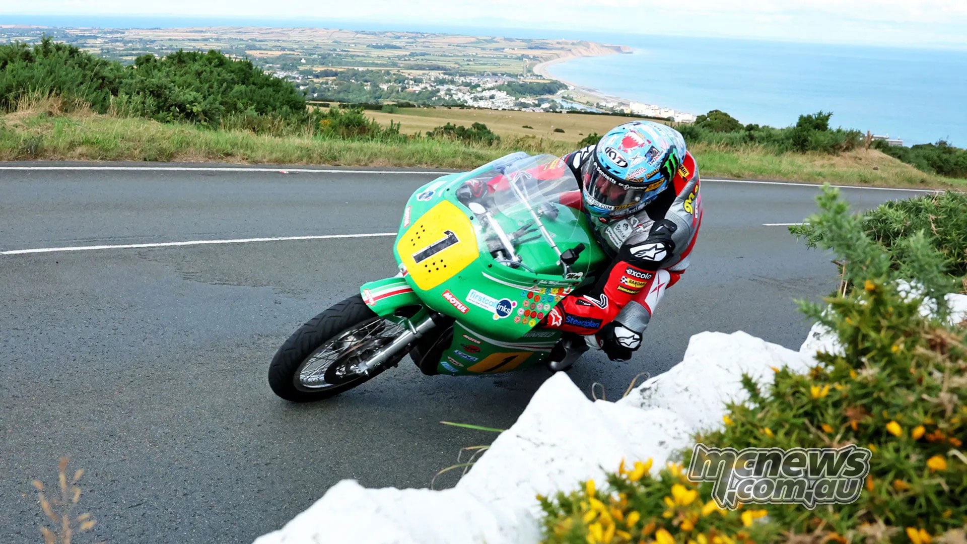 John McGuinness rides his green Paton around a bend overlooking the Isle of Man coastline