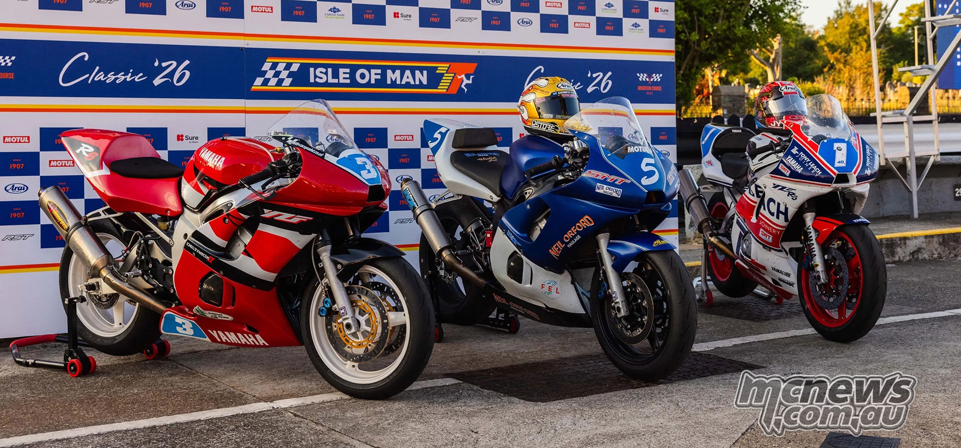 Three Yamaha race motorcycles are displayed in front of the Classic TT podium backdrop