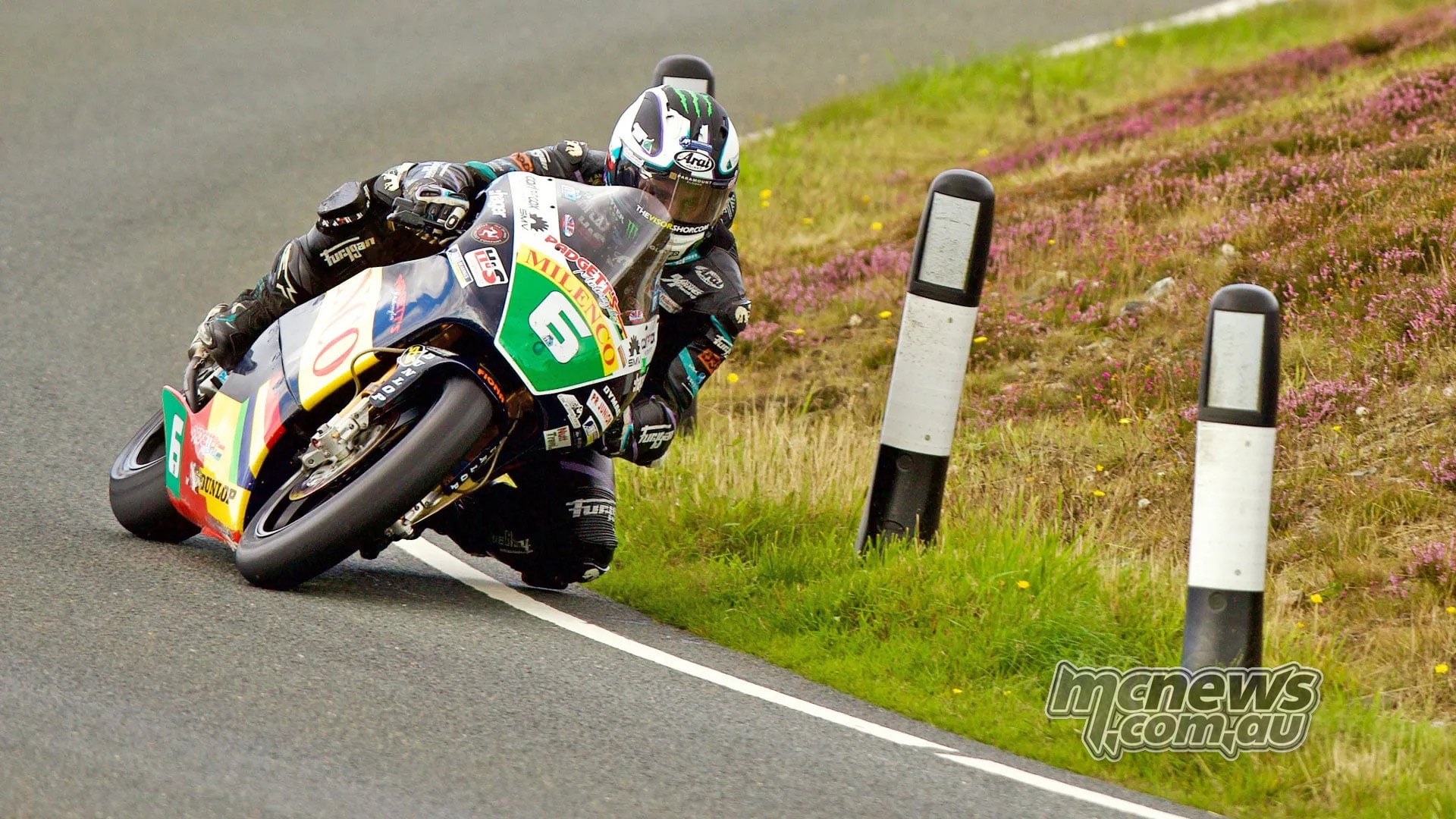 Michael Dunlop corners on his yellow and green number six Honda two-stroke