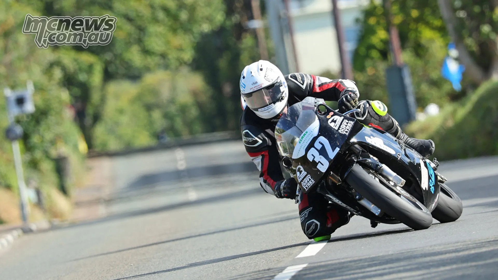 Joe Loughlin leans his black number 32 motorcycle through a bend