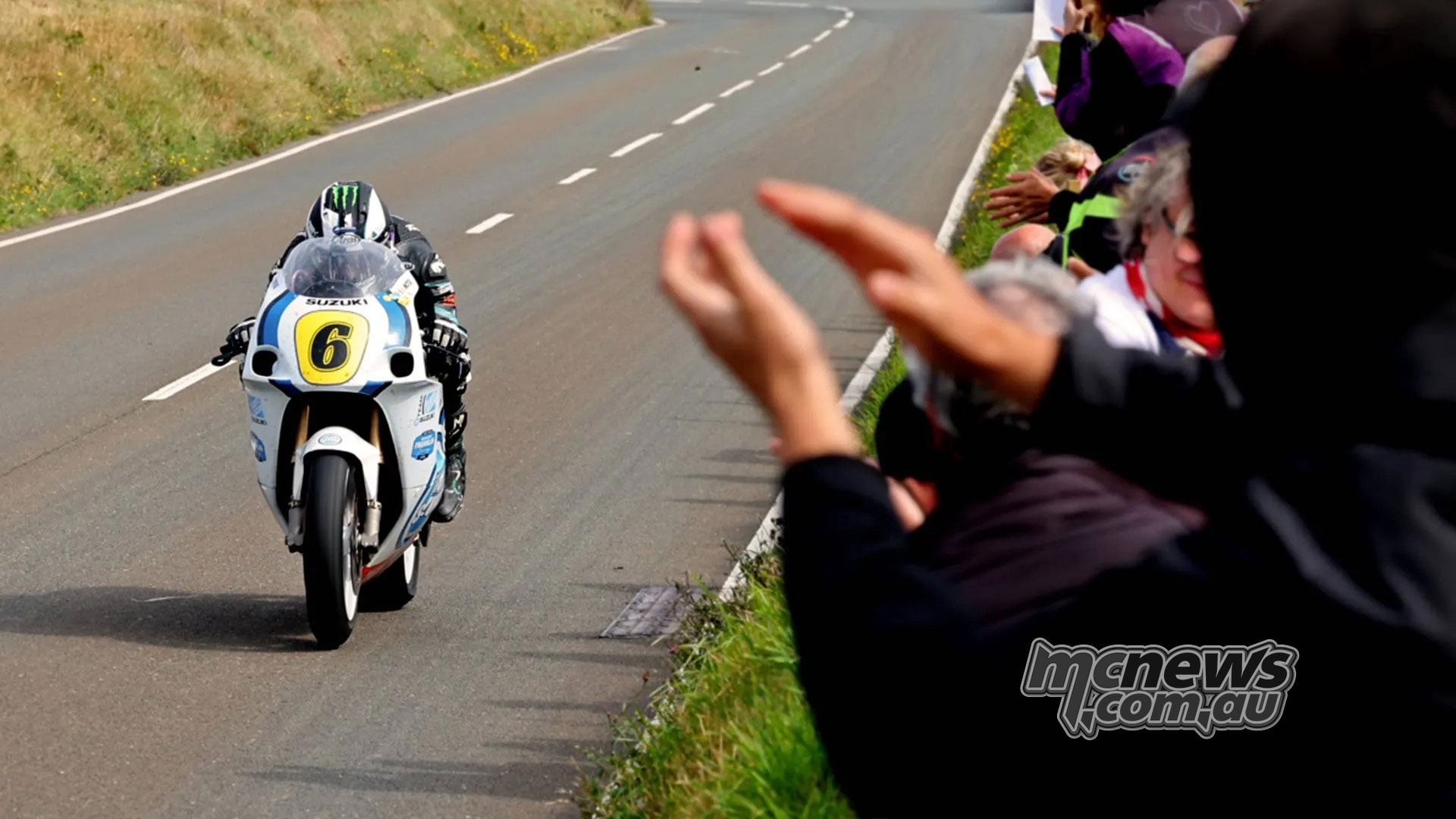 Spectators applaud as Michael Dunlop approaches on his number six Suzuki