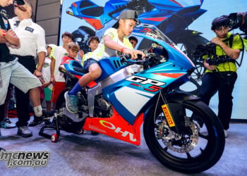 Young rider sitting on the Ohvale GP-5 250 during its unveiling as other children watch.