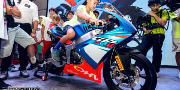 Young rider sitting on the Ohvale GP-5 250 during its unveiling as other children watch.