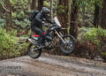 Rider standing on the footpegs while jumping a Rieju Aventura Rally 307 over a trail crest