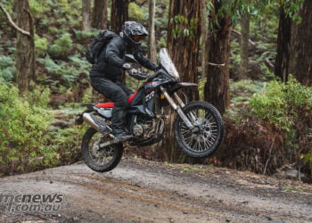 Rider standing on the footpegs while jumping a Rieju Aventura Rally 307 over a trail crest