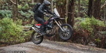 Rider standing on the footpegs while jumping a Rieju Aventura Rally 307 over a trail crest