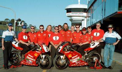 The Ducati Dealer Team poses with two red race bikes in pit lane at Eastern Creek in 1999.