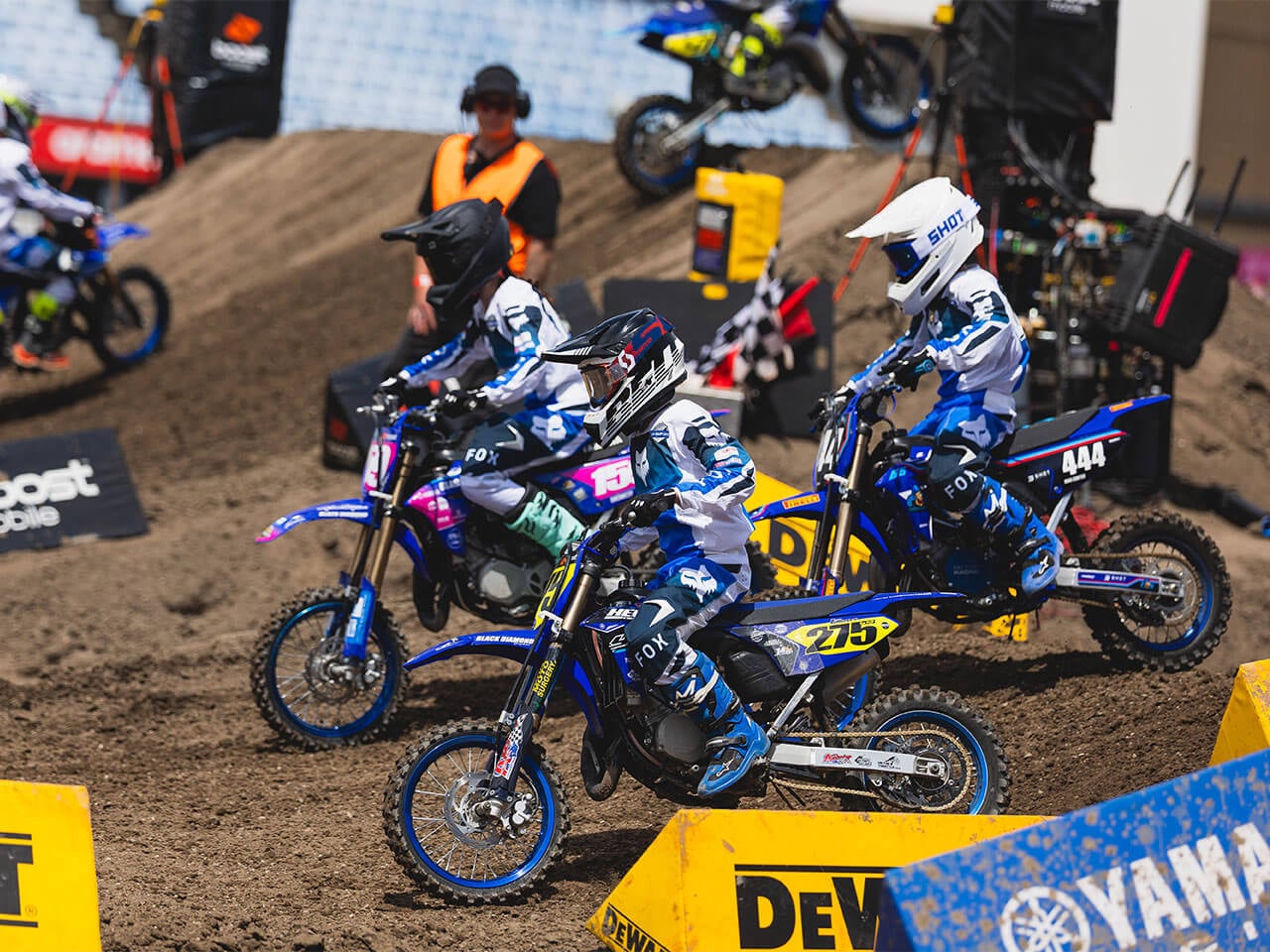 Three young Yamaha YZ65 riders negotiating a Supercross section together
