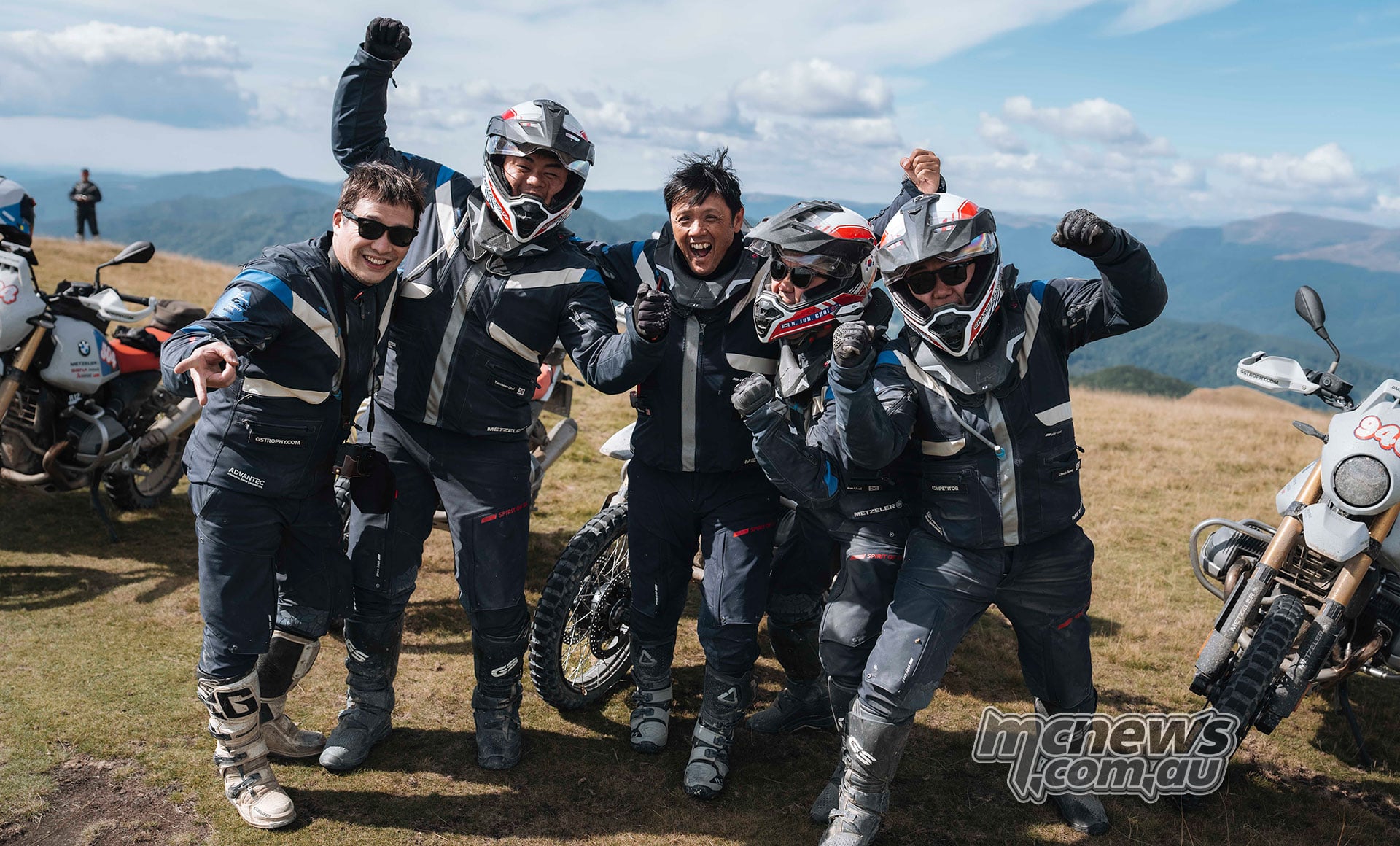 Four GS Trophy participants pose together beside their motorcycles on a mountain plateau in Romania.