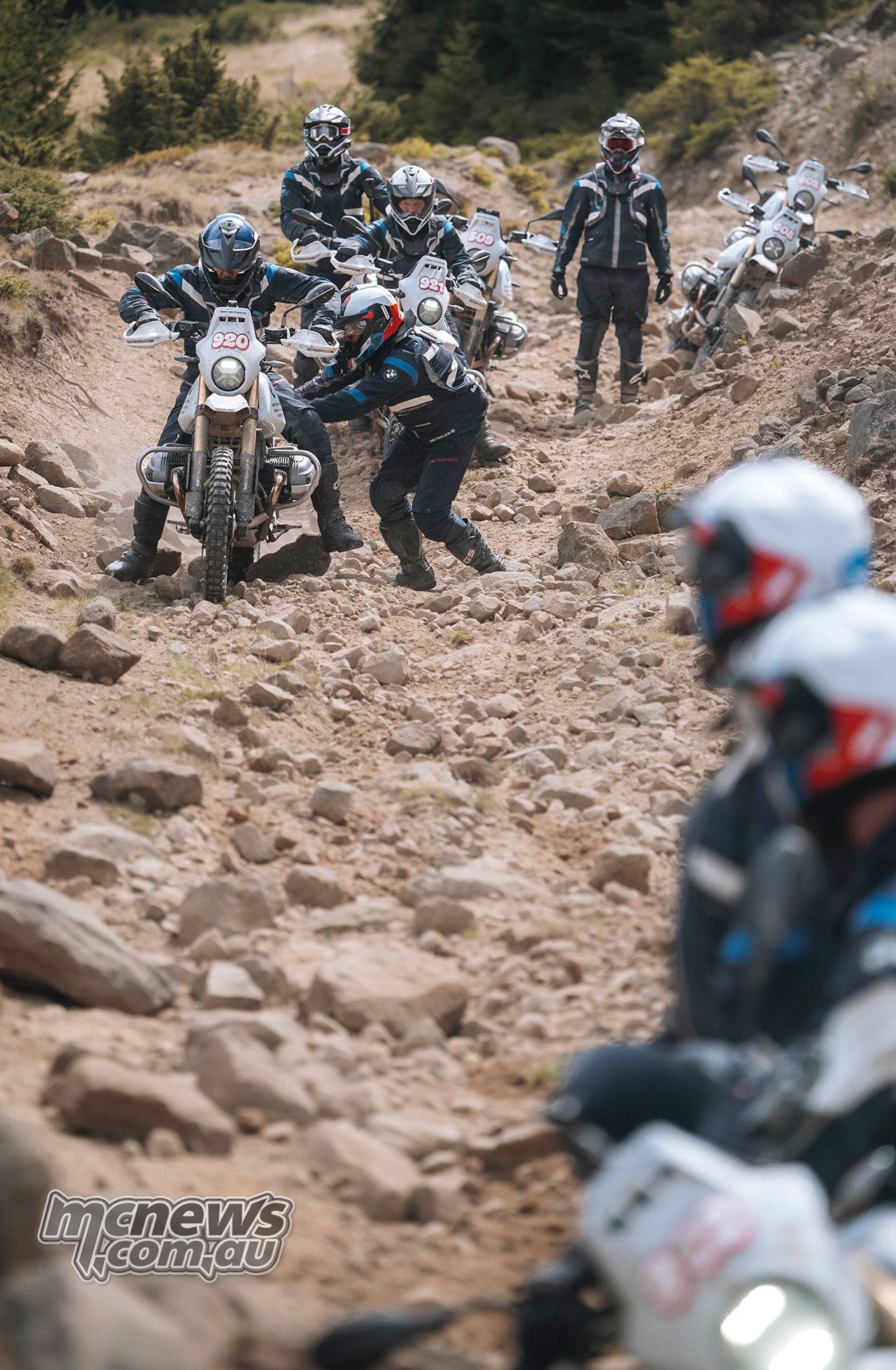 GS Trophy riders work together to move a BMW R 12 G/S up a steep, rocky track.