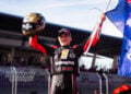 Archie McDonald raises an Australian flag and his gold helmet while wearing the Bagger World Cup champion’s bib at the Red Bull Ring.