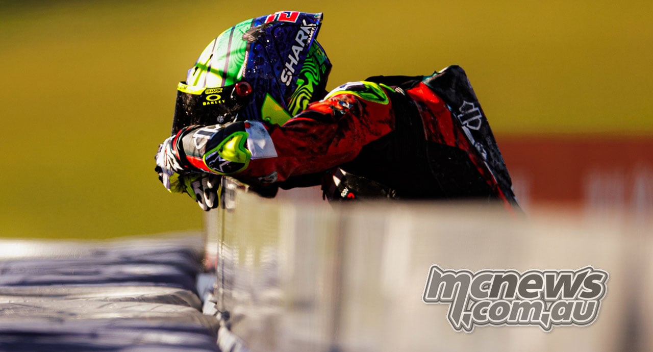 Eric Granado rests his helmet on his folded arms at a trackside barrier after the Race One crash.