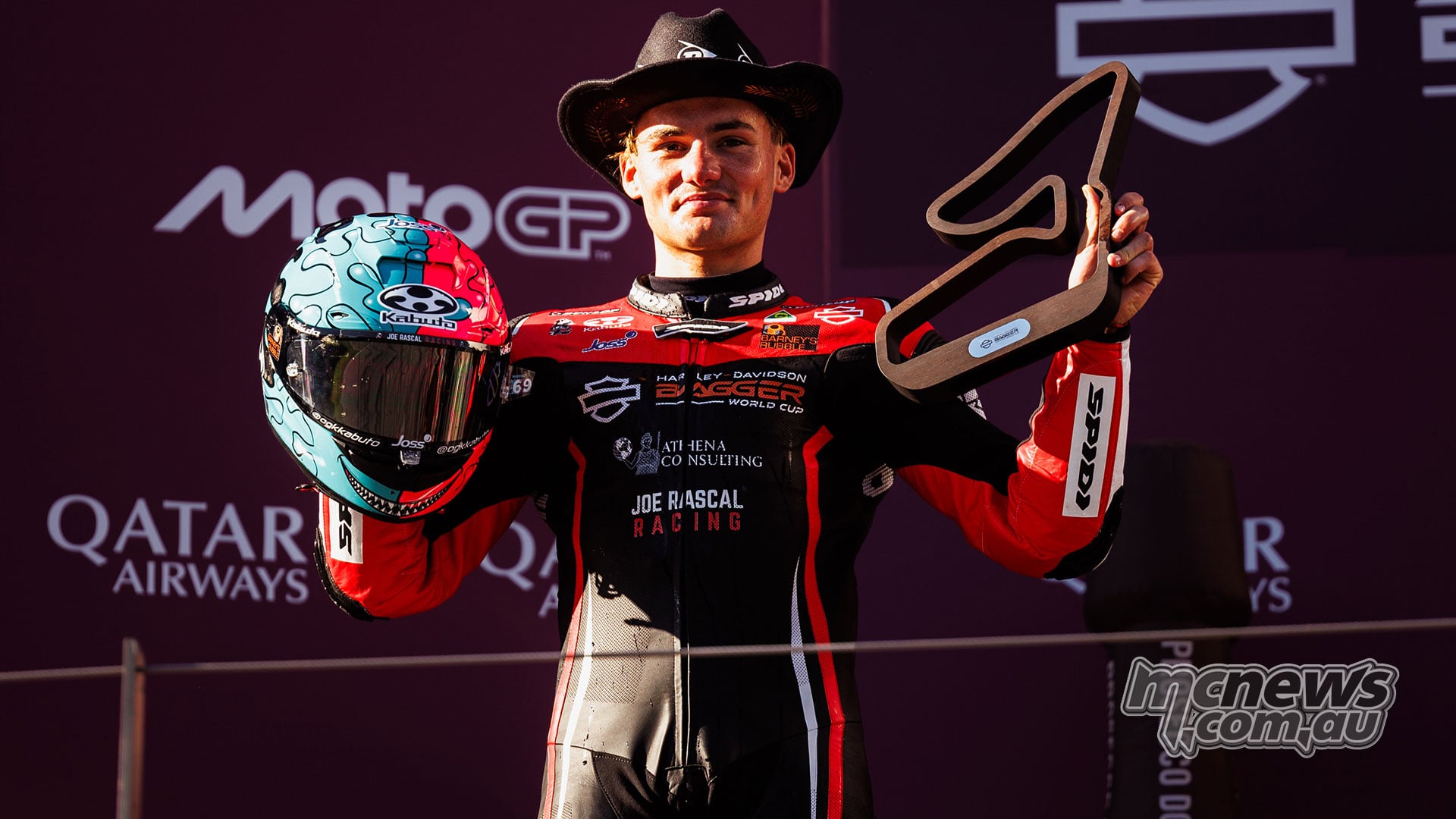 Archie McDonald wears a cowboy hat and holds his helmet and Race One second-place trophy on the Red Bull Ring podium.