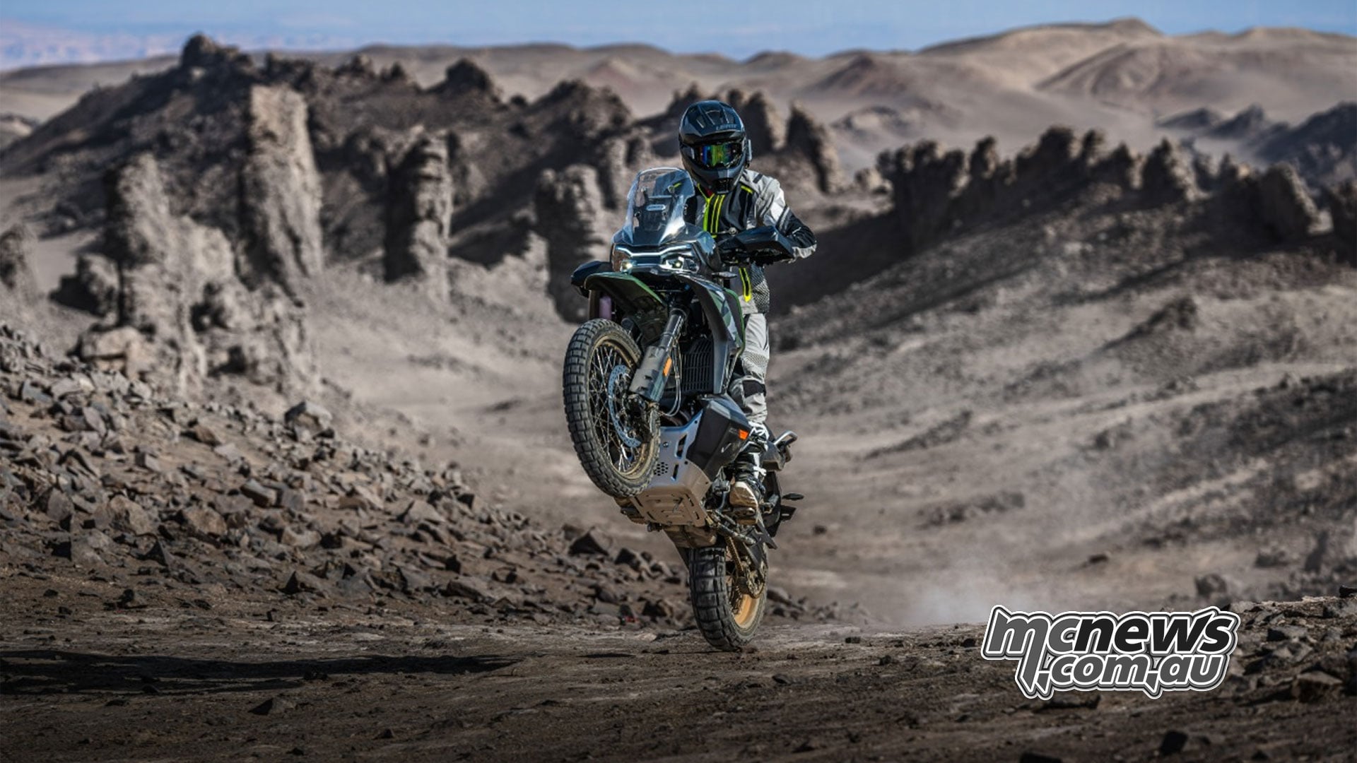 A rider lifts the front wheel of a CFMOTO 1000MT-X on a rocky trail.