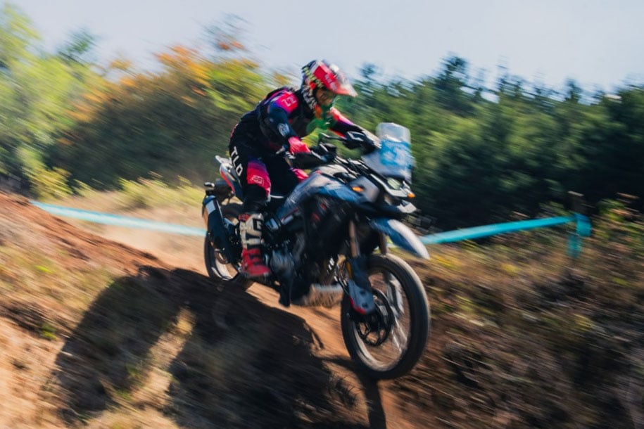 An MT Challenge competitor rides through a dirt section bordered by blue course tape.