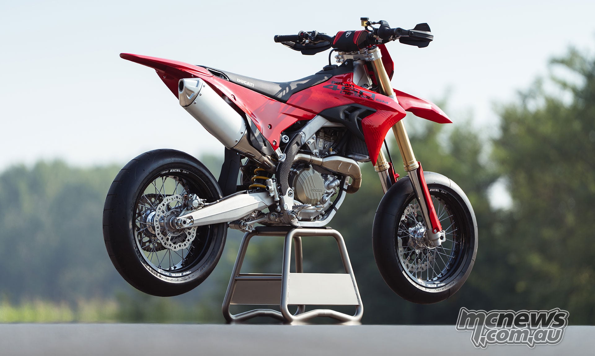 Low rear three-quarter view of the Ducati Desmo450 SM on a stand, showing the exhaust silencer, aluminium swingarm and rear slick tyre.