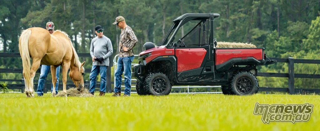 Red Honda Pioneer SXS1000-3 Deluxe beside three people and a horse in a paddock