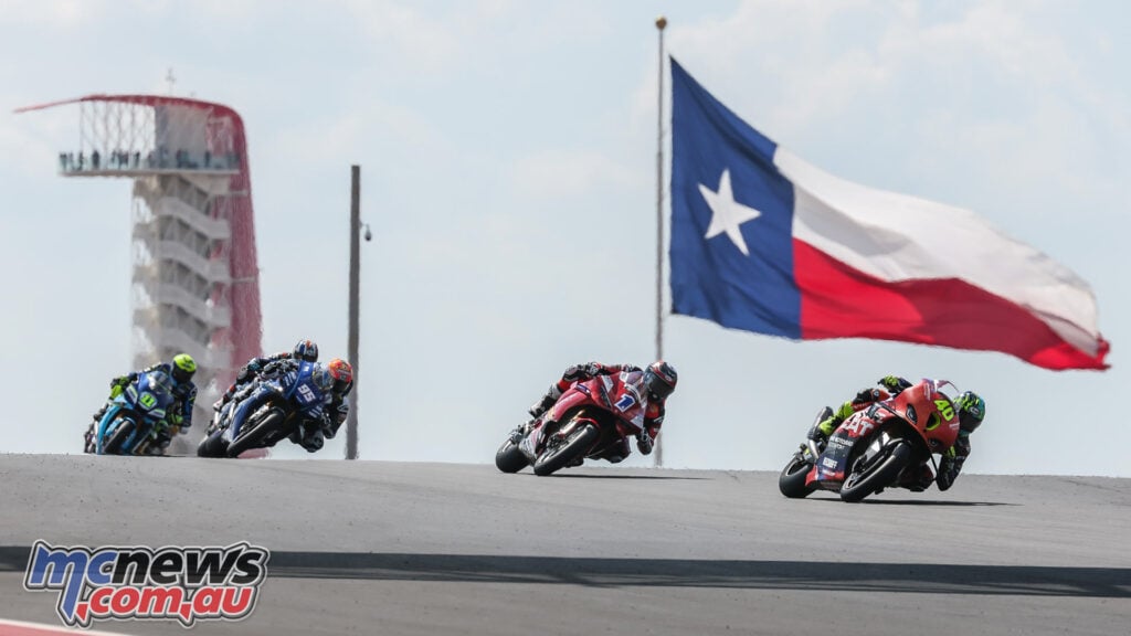 Sean Dylan Kelly leads a line of Superbikes over a crest beneath a large Texas flag at COTA.