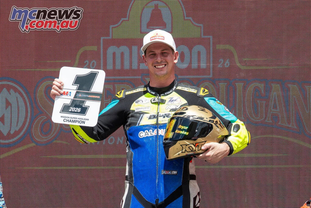Bryce Kornbau holds the Super Hooligan champion number-one plate and a gold helmet on the podium.