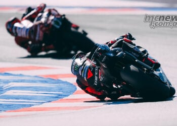 Rear view of Marco Bezzecchi's Aprilia following Marc Marquez's Ducati through a Misano corner.