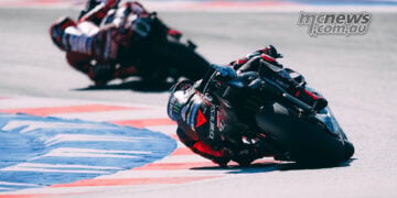 Rear view of Marco Bezzecchi's Aprilia following Marc Marquez's Ducati through a Misano corner.
