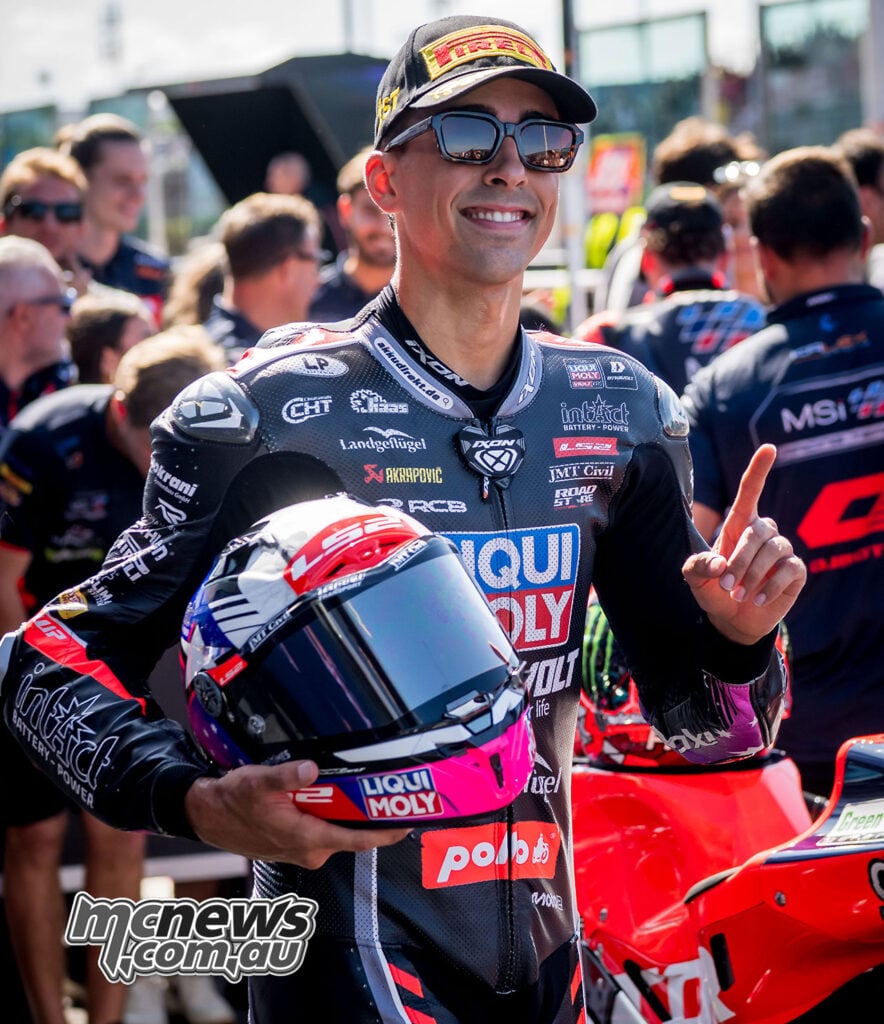 Senna Agius smiles, holds his helmet and raises one finger after securing Moto2 pole at Misano.