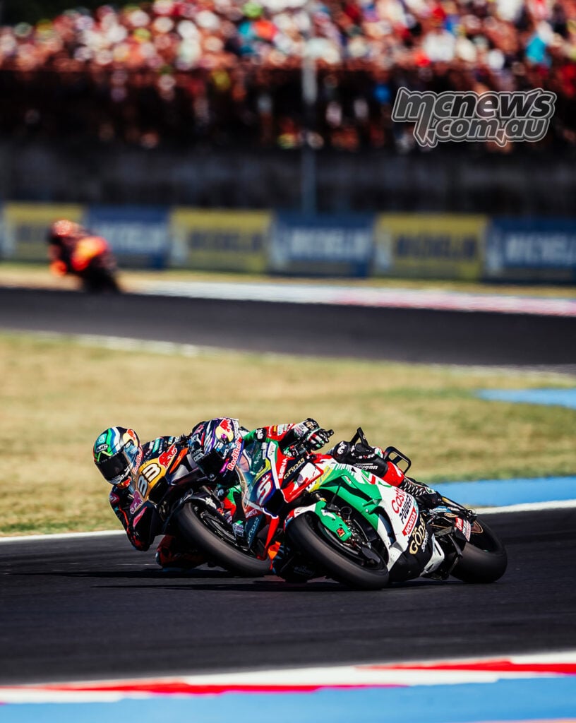 Brad Binder and Johann Zarco run close together through a Misano corner, with spectators in the background.