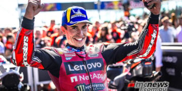 Marc Marquez smiles and raises both arms in parc ferme after winning the Misano MotoGP race.