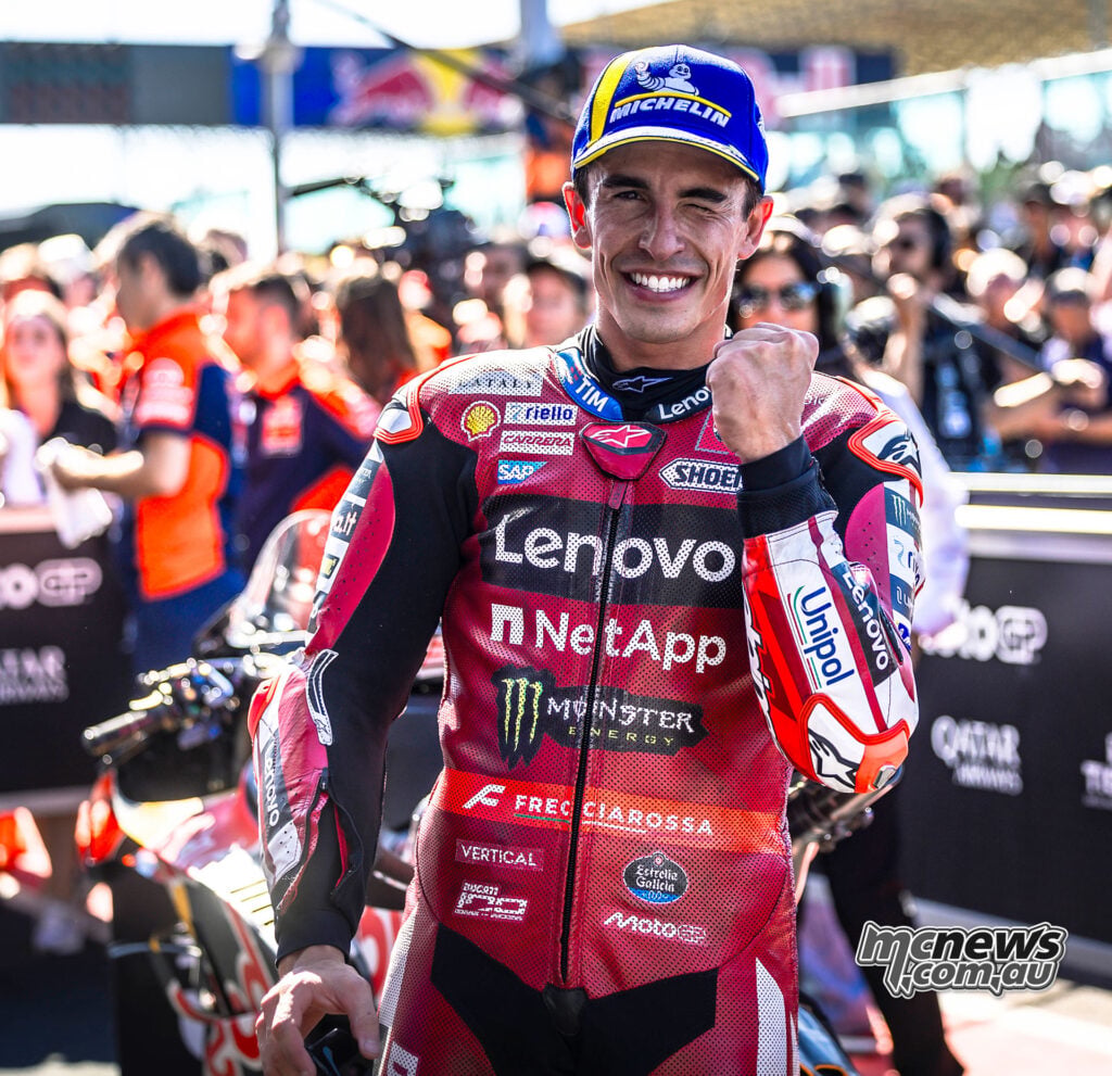 Marc Marquez smiles with one eye narrowed and holds up a clenched fist in parc ferme.