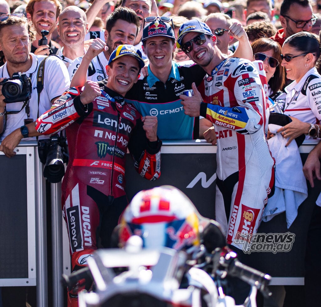Marc and Alex Marquez smile together among a group celebrating in parc ferme at Misano.