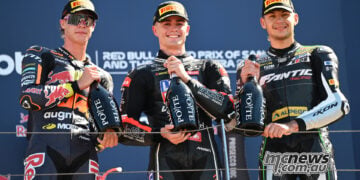 Collin Veijer, Manuel Gonzalez and Barry Baltus stand together holding bottles on the Misano Moto2 podium.