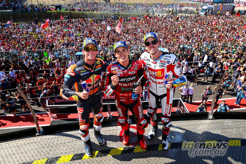 Pedro Acosta, Marc Marquez and Alex Marquez pose together above the packed spectator area at Misano.