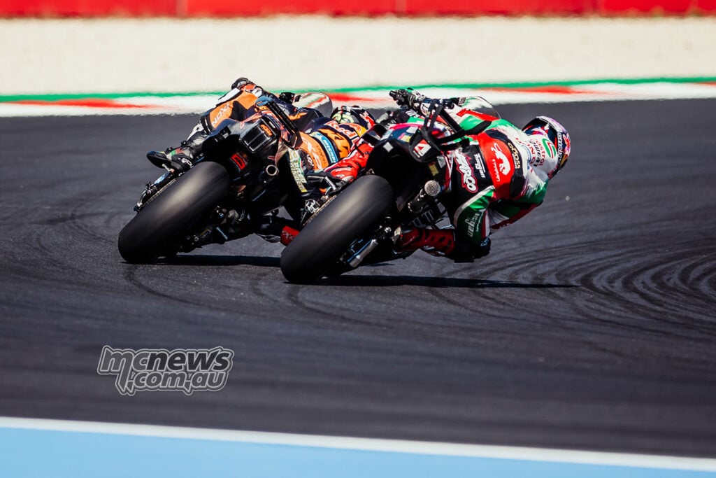 Johann Zarco’s Honda runs ahead of Brad Binder’s KTM as both riders lean through a corner.