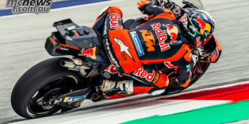 Rear three-quarter view of Pedro Acosta cornering on his Red Bull KTM beside the Red Bull Ring kerbing.