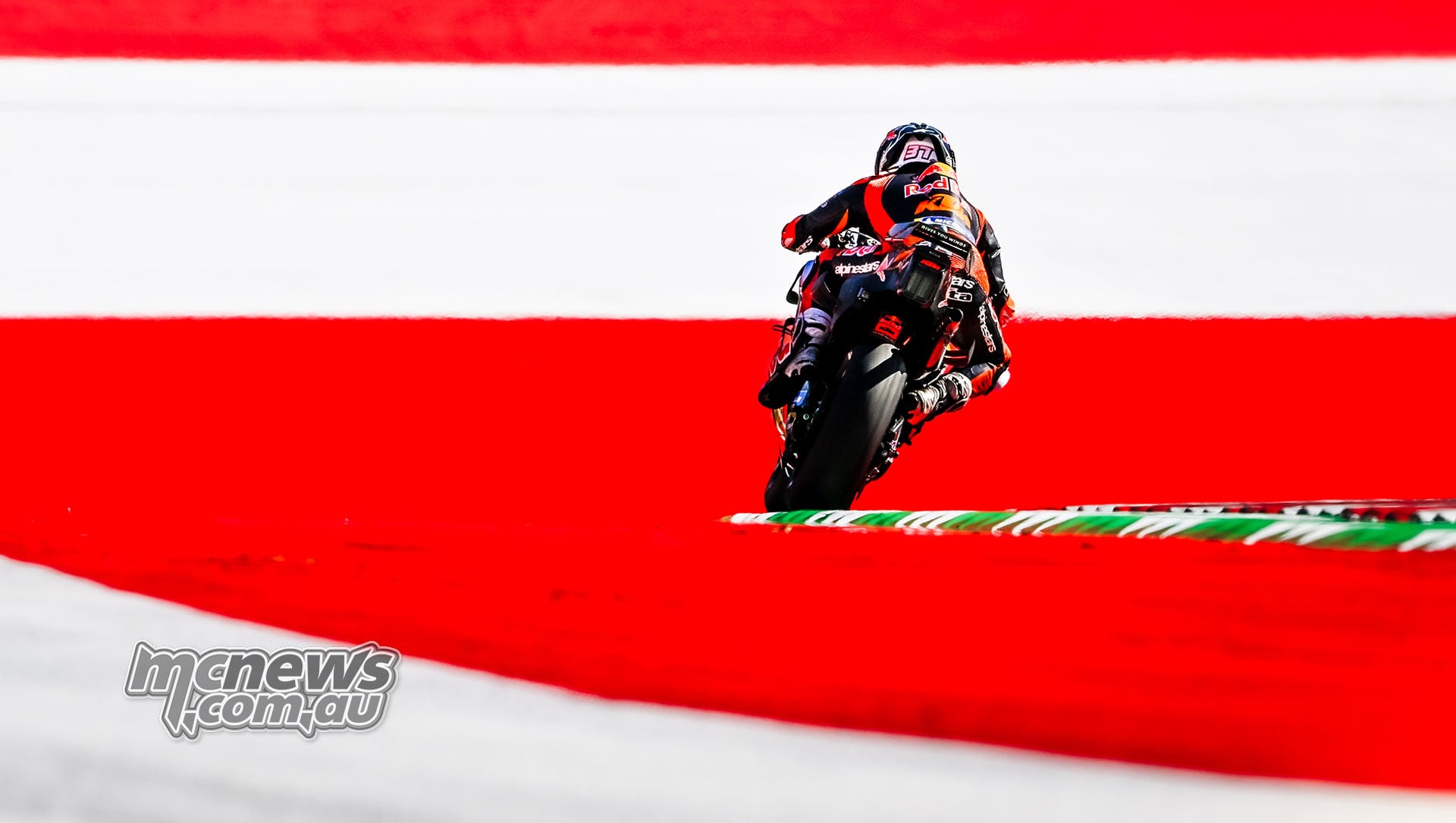 Pedro Acosta rides his KTM past red-and-white trackside barriers at the Red Bull Ring.