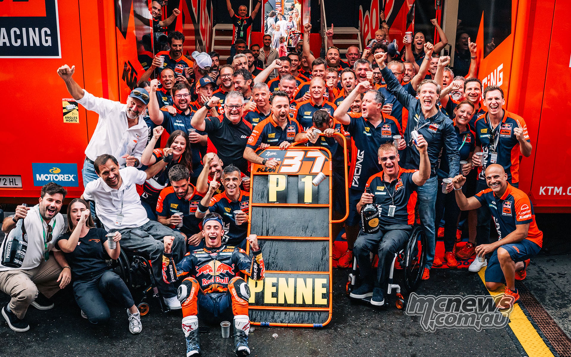 Pedro Acosta poses with the KTM team, the winner’s trophy and a P1 pit board.