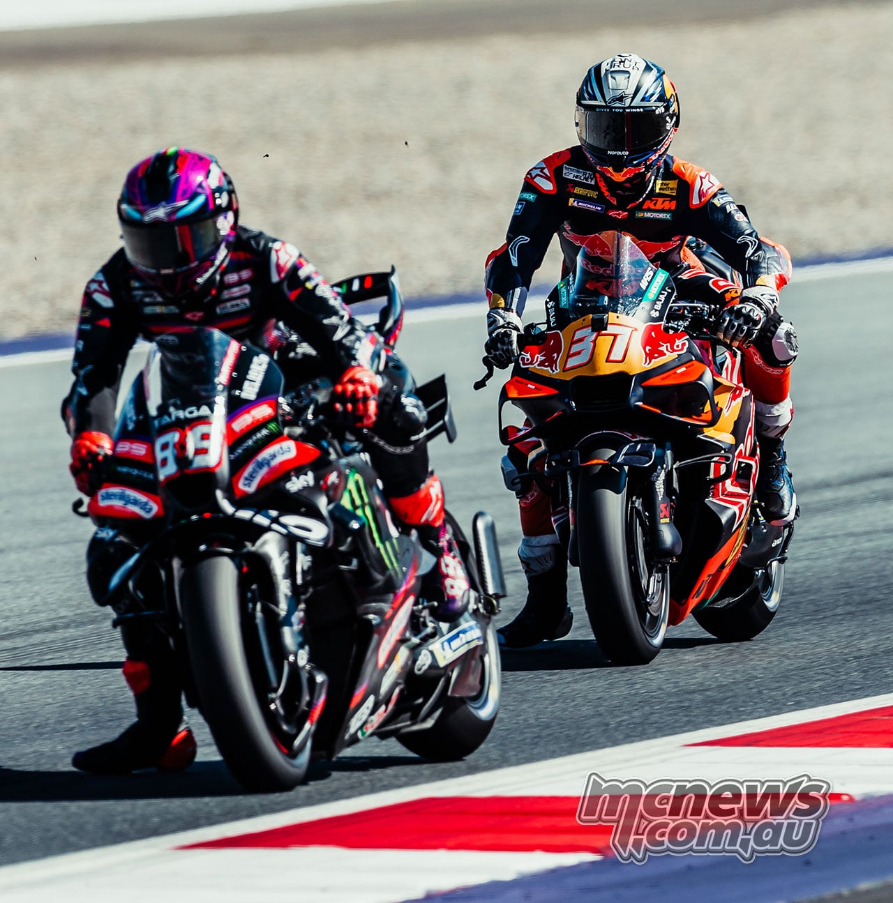 Jorge Martin brakes ahead of Pedro Acosta, both riders extending a leg beside their motorcycles.