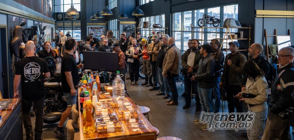 Royal Enfield One Ride 2026 participants gathered inside a Sydney motorcycle showroom beside bikes and a table of refreshments.