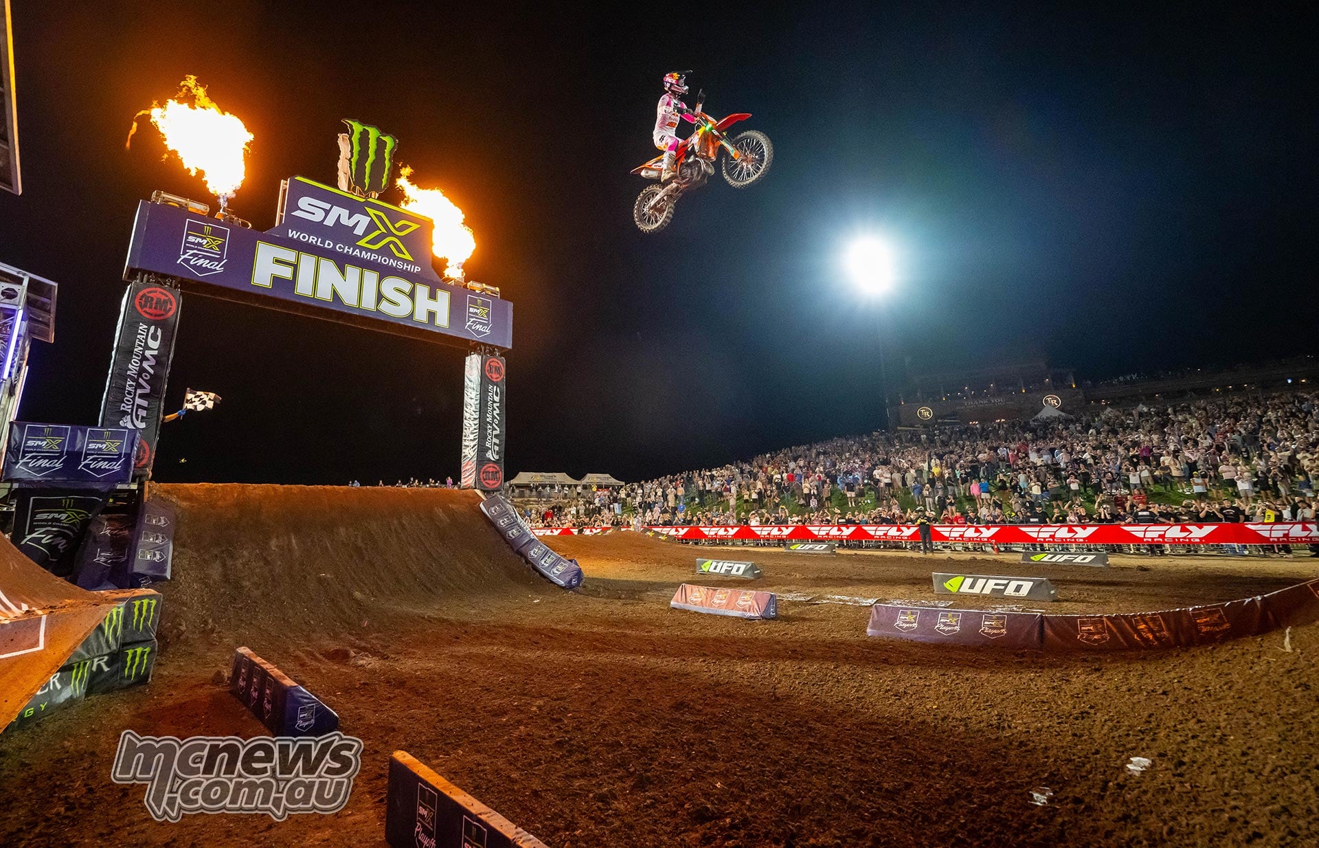 Jorge Prado jumps across the finish line between columns of flame.