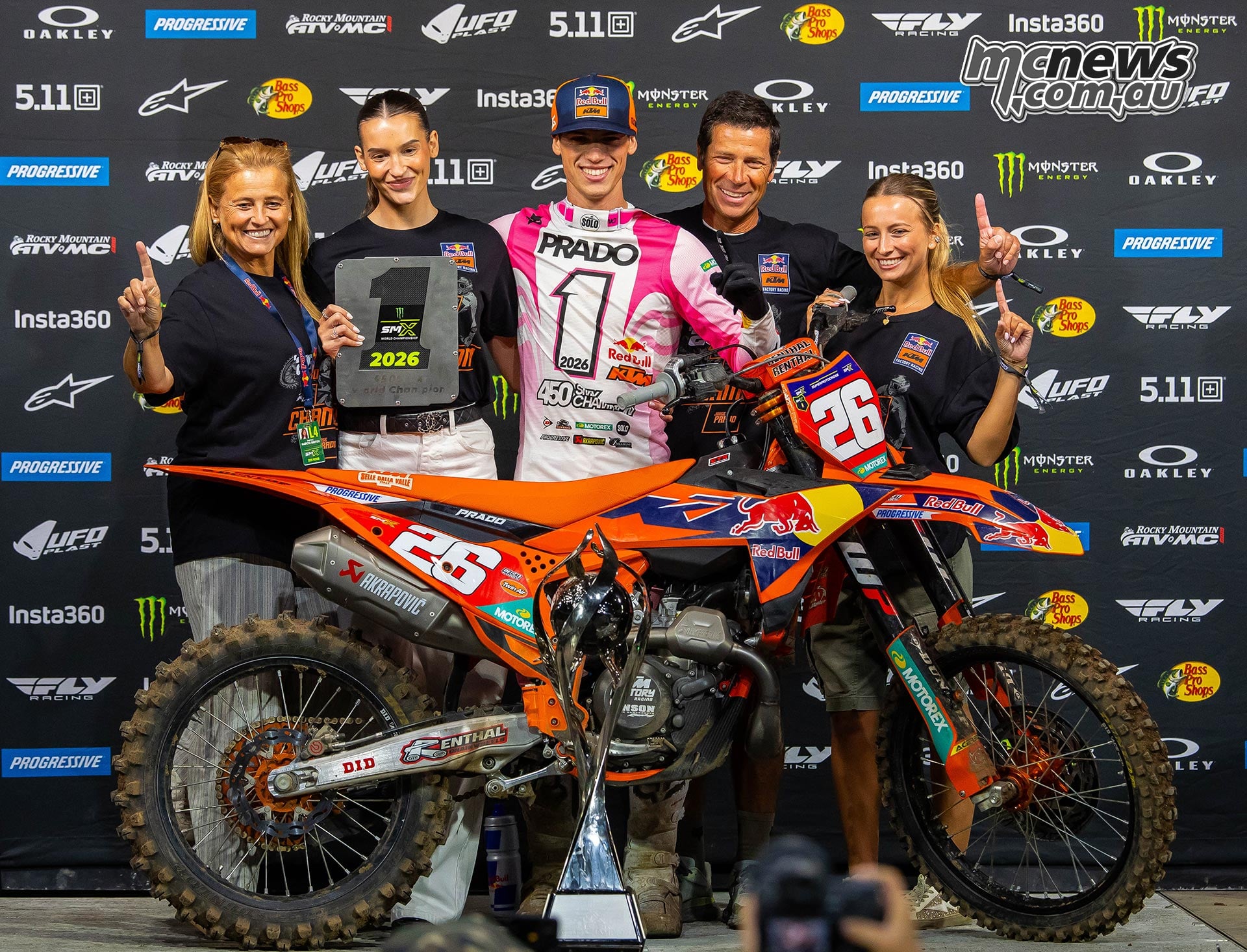 Jorge Prado celebrates on the podium with a group gathered around his number 26 KTM.
