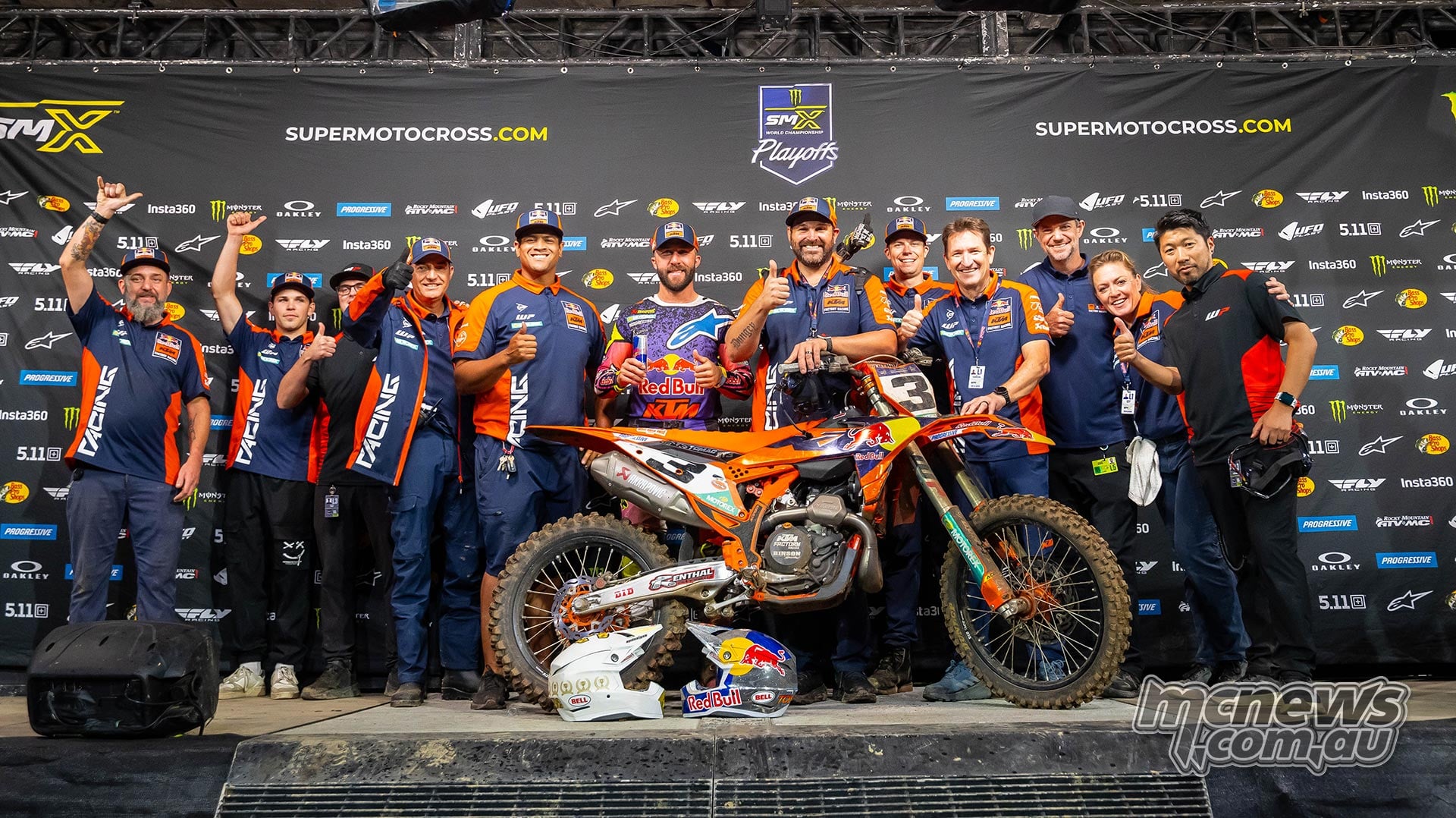 Eli Tomac and his KTM team gather around his motorcycle on the podium.