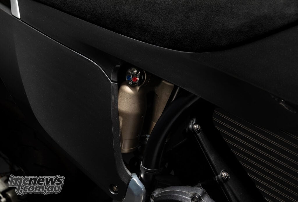 Close-up of the Stark VARG SM Sköll’s rear shock reservoir and coloured damping adjusters beneath the seat.