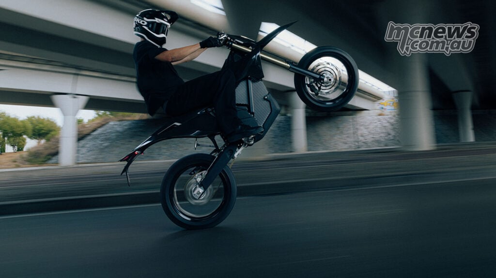 Side view of a rider lifting the front wheel of a black Stark VARG SM Sköll beneath an overpass.