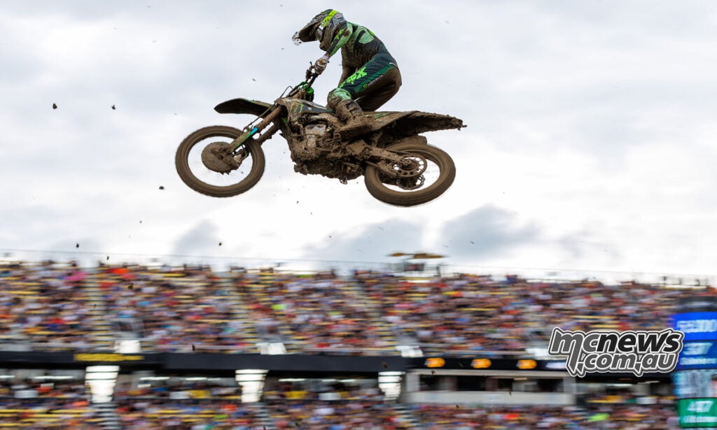 Levi Kitchen flies high above the Columbus track on his mud-covered Kawasaki, with packed grandstands behind.