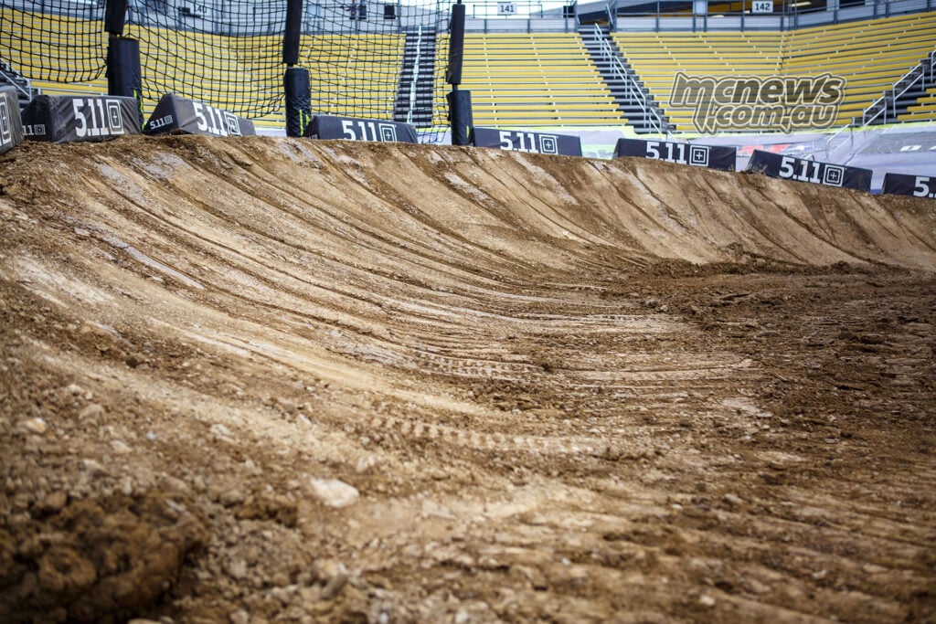 Freshly prepared banked corner on the Columbus SMX track, with grooming marks and empty yellow grandstands.