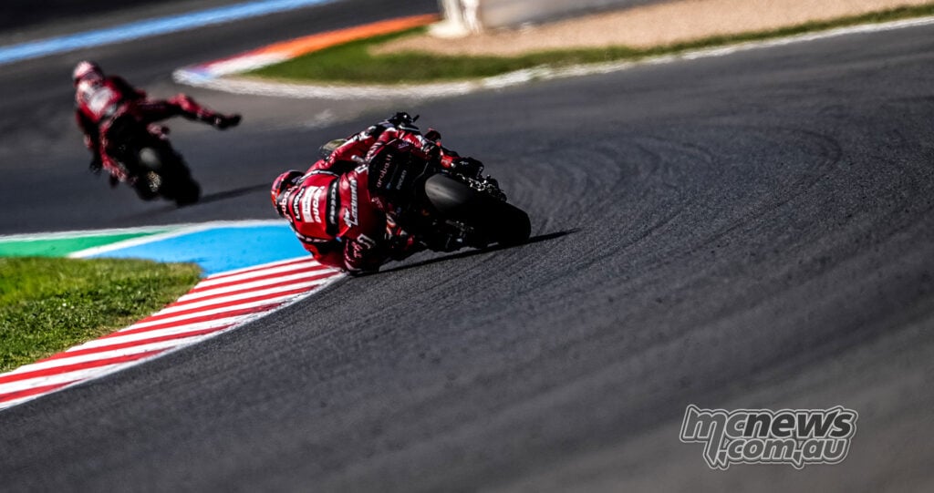 Rear view of Nicolo Bulega and Iker Lecuona leaning their red Aruba.it Racing Ducatis through a Magny-Cours corner.